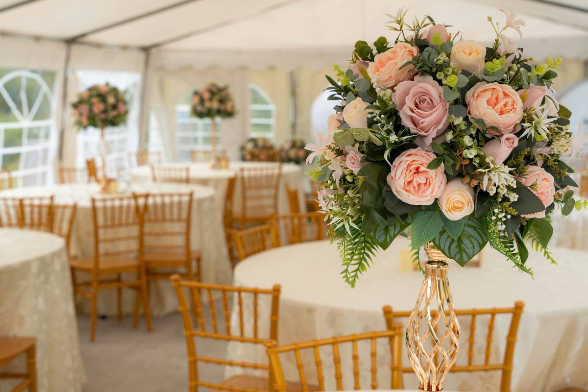 simple and elegant wedding decor: ivory linen runner, single stem white peonies in matte ceramic vase, and unlit tapered ivory candle on rustic wood table